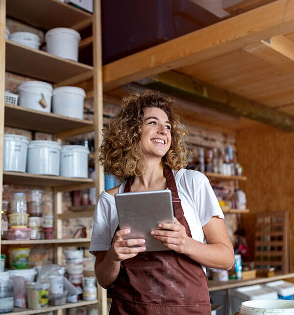 Handwerkerin mit Tablet-Computer in ihrem Unternehmen ist glücklich, einen Eintrag auf FirmenABC zu haben.