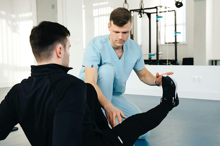 Ein Orthopäde behandelt das Bein eines Patienten.