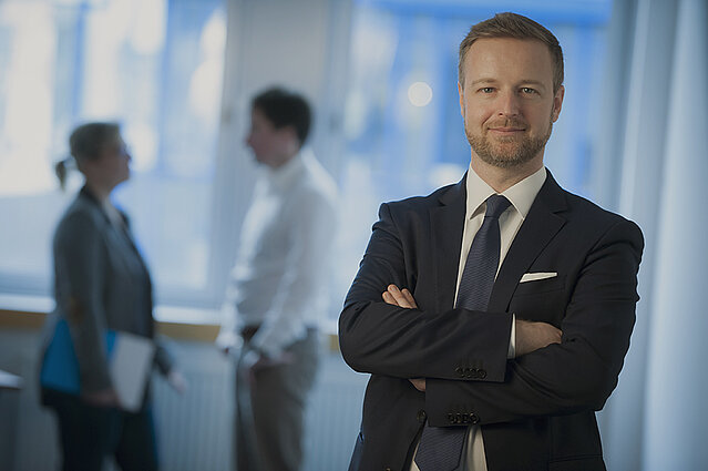 Erfolgreicher Mann steht im Büro von Creditreform. 