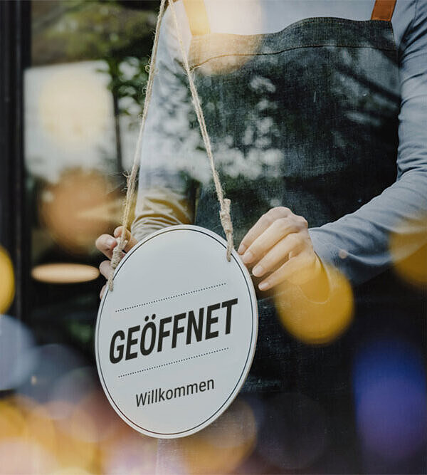 "Geöffnet"-Schild an der Glastür eines Coffee-Shops. Durch Google Werbung bekommt das Unternehmen mehr Sichtbarkeit.