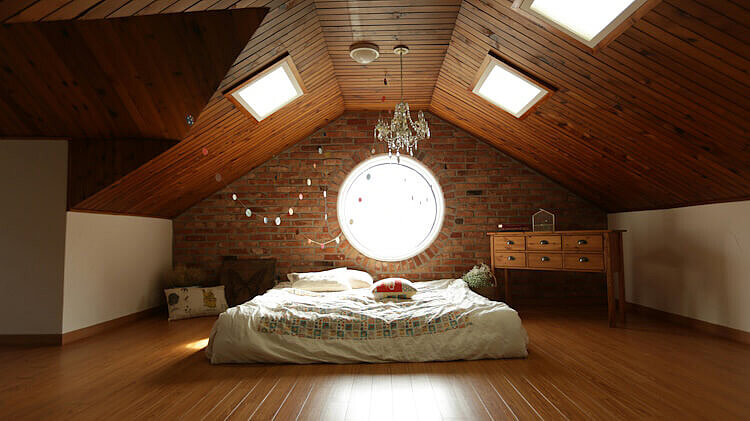 Ein warm eingerichtetes Dachgeschosszimmer mit Holzdecke. 