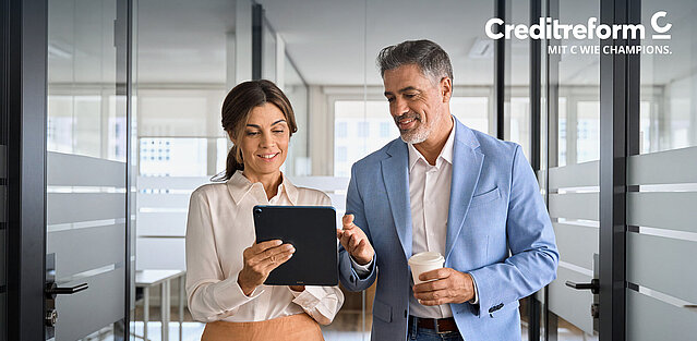 Eine Frau und ein Mann besprechen am Tablet Business Strategien im Büro.