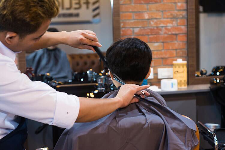 Ein Mann lässt sich beim Friseur die Haare schneiden.