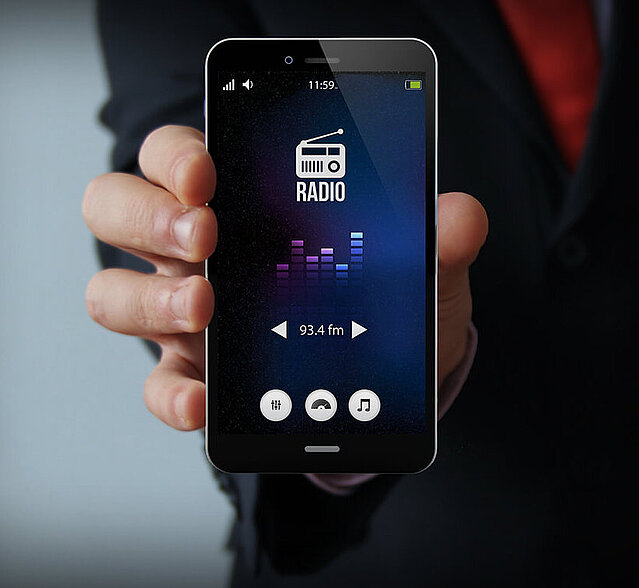 Mann zeigt Smartphone mit App für Digitalradio.